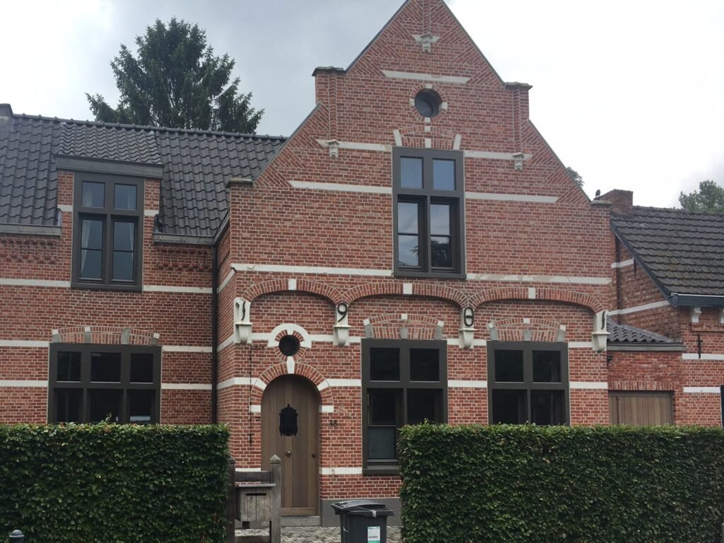 Totaalproject met donker houten buitenschrijnwerk en massieve voordeur in een karaktervolle bakstenen gevel.